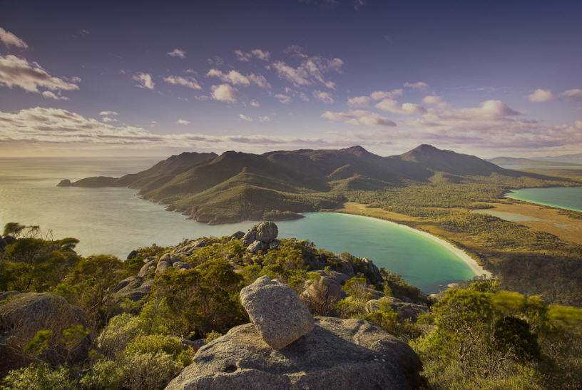 Aerial photo of Freycinet National Park, showcasing the dramatic coastline with white sand beaches, rocky headlands, and the turquoise waters of the Tasman Sea.