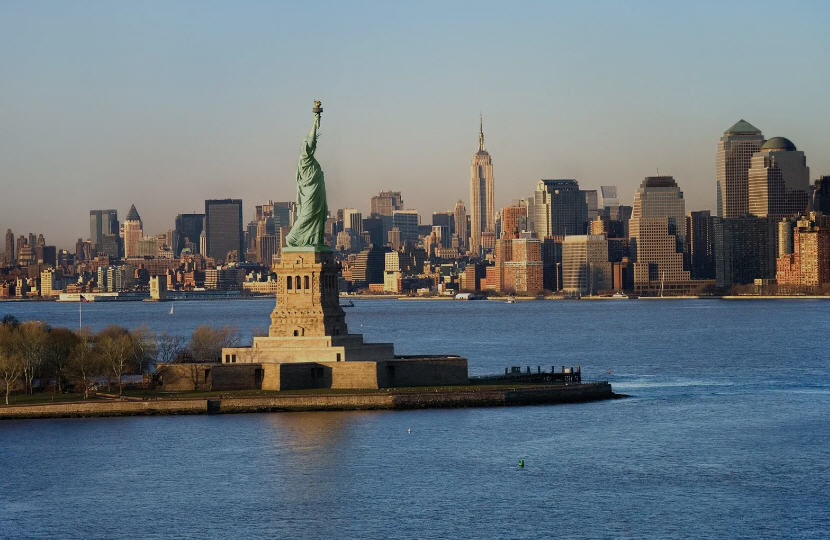 Iconic New York City skyline, featuring the Empire State Building, Chrysler Building, and the Statue of Liberty in the distance.