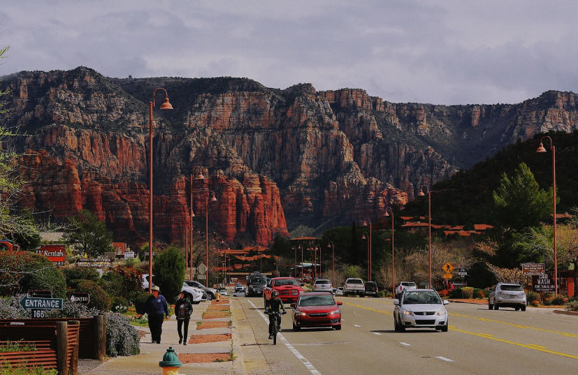 Red rock formations of Sedona, Arizona, with green juniper trees and a vibrant blue sky.