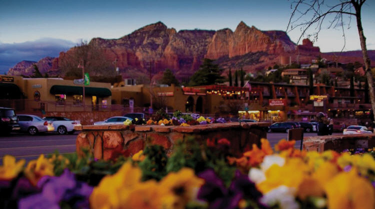 Panoramic view of Sedona, showing the town nestled amidst towering red rock buttes and distant mountains.