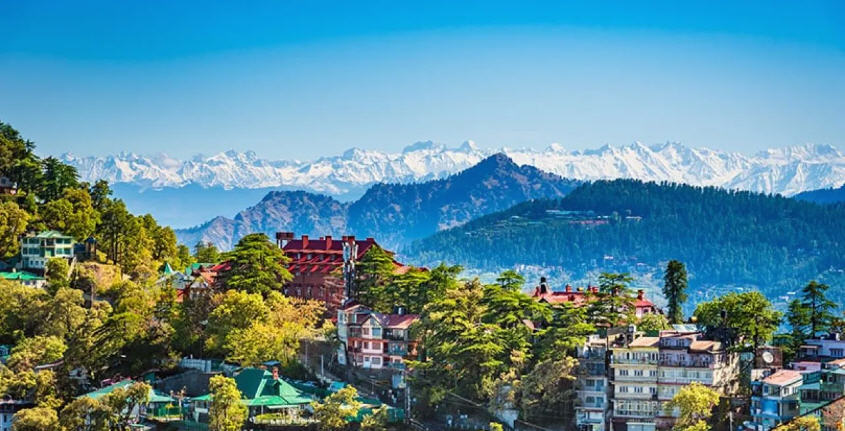 Panoramic view of Shimla, nestled in the rolling Himalayan foothills, with colonial-era buildings and lush green forests.