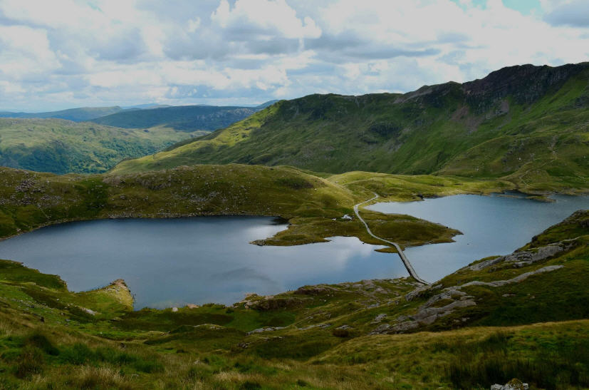 Sweeping view of Snowdonia National Park, Wales, featuring rugged mountains, glacial lakes, and lush green valleys.