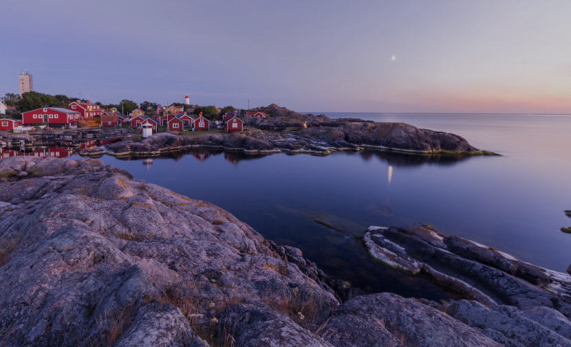 Sweeping view of the Stockholm Archipelago, showcasing a cluster of islands with lush greenery, colorful houses, and boats dotting the Baltic Sea.