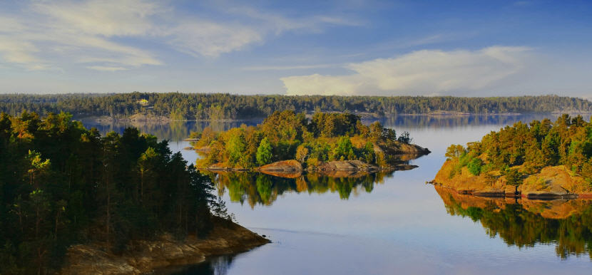Vibrant sunset over the Stockholm Archipelago, casting long shadows across the islands and turning the sea golden.