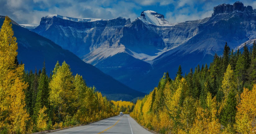 Sweeping view of Jasper National Park, featuring snow-capped Rocky Mountain peaks, turquoise lakes, and dense evergreen forests.